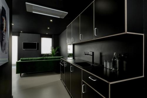 a kitchen with black cabinets and a green couch at Kip Hotel in London