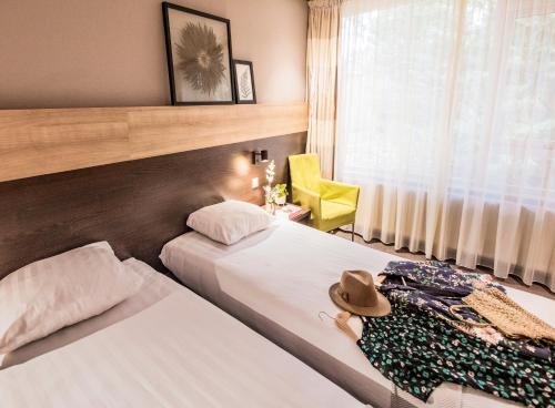 a hotel room with two beds and a yellow chair at Buitenplaats de Bergse Bossen in Driebergen