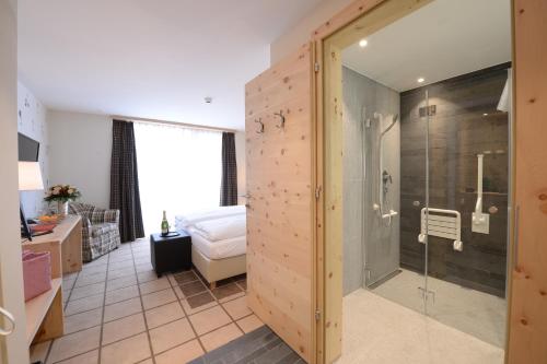 a bathroom with a shower and a bed in a room at Alpenhotel Fleurs de Zermatt in Zermatt