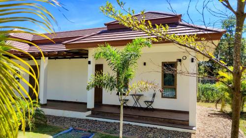 a small white house with a wooden porch at Isan Golf & Adventure Hotel in Udon Thani