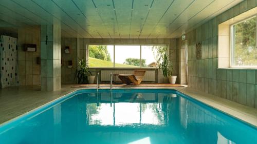 a swimming pool in a house with a window at Hotel "Haus am Berg" in Rinchnach