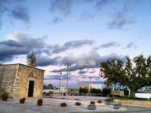 a building with a tree and a cloudy sky at Dimora San Quirico - bed e breakfast - Cisternino in Cisternino