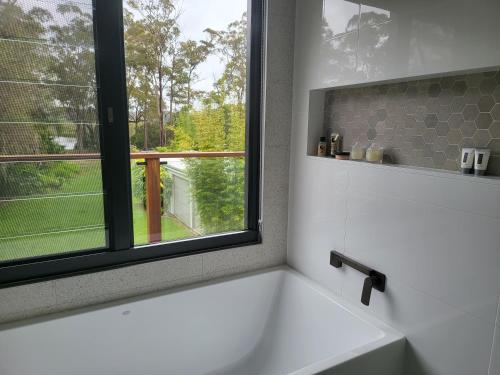 uma banheira branca na casa de banho com uma janela em Jervis Bay Waters Edge Retreat - Access to Deep Water - Free late check out 2pm on Sundays, low season em Woollamia