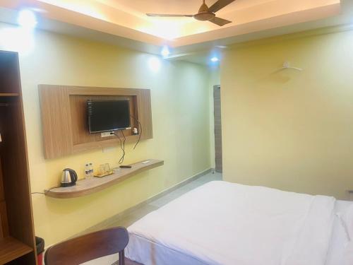 a bedroom with a bed and a tv on the wall at Royal Beach International in Puri