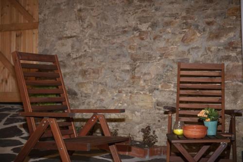 two wooden chairs sitting next to a stone wall at Vale das Maias - Casa de Campo in Laborins