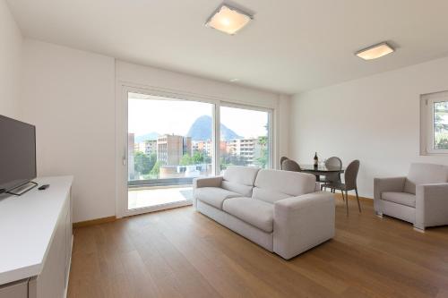 un soggiorno bianco con divano, tavolo e finestra di Roggia 16 by Quokka 360 - central flat with balcony a Viganello