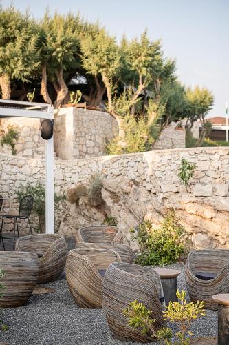 a garden with wooden chairs and a stone wall at Kakkos Bay Hotel and Bungalows in Ierápetra