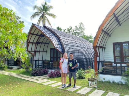 a man and woman standing in front of a house at Gino's Place - Guest House & Jungle Trekking in Bukit Lawang