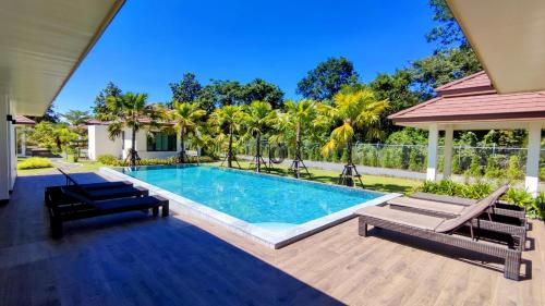 a swimming pool with two lounge chairs and a house at Isan Golf & Adventure Hotel in Udon Thani