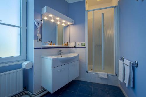 La salle de bains bleue est pourvue d'un lavabo et d'une douche. dans l'établissement Hôtel Miléade Le Domaine de la Blairie - Saumur, à Saint-Martin-de-la-Place