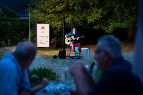 a woman sitting on a stage with a guitar at Hôtel Miléade Le Domaine de la Blairie - Saumur in Saint-Martin-de-la-Place
