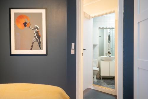 a bedroom with a painting on the wall and a bathroom at The Golden Lion Street Getaway in Trondheim