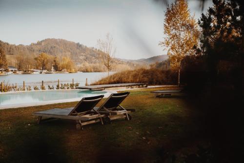 two lounge chairs sitting on the grass next to a lake at Luxury glamping Chocolate village in Maribor