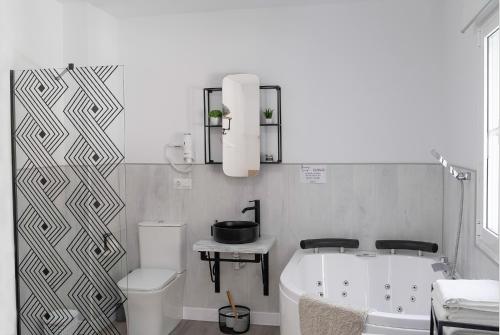 a bathroom with a tub and a toilet and a sink at Casa Rural Las Cuevas de Setenil in Setenil