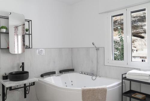 baño blanco con bañera y ventana en Casa Rural Las Cuevas de Setenil, en Setenil