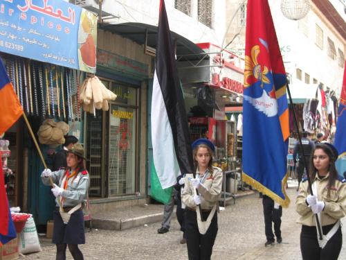 a group of girls holding flags in a street at BREAD HOUSE in Bethlehem