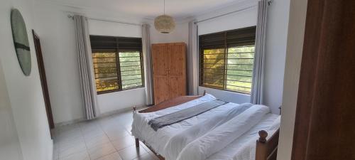 a bedroom with a bed and two windows at Nature Kigali in Kigali