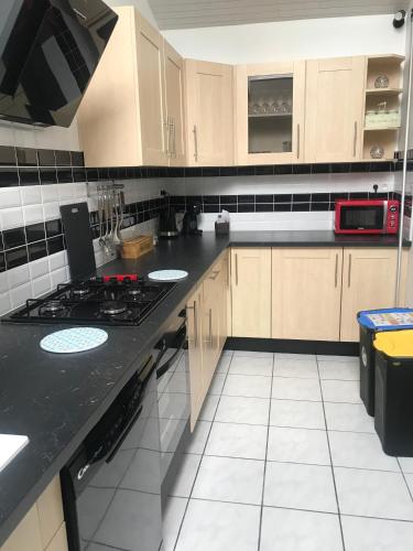 a kitchen with a black counter top and wooden cabinets at Gite Super Henanbihen in Hénanbihen