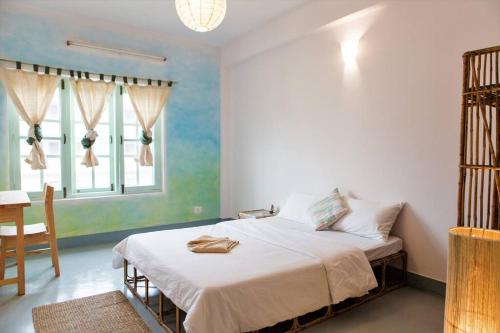 a bedroom with a bed and a table and a window at Ananda Tree House Eco Homestay in Kathmandu