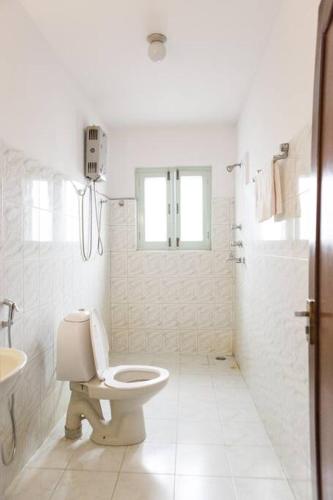 a white bathroom with a toilet and a sink at Ananda Tree House Eco Homestay in Kathmandu
