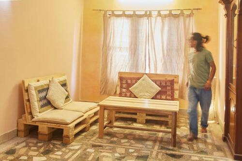 a man standing in a room with two chairs and a table at Ananda Tree House Eco Homestay in Kathmandu