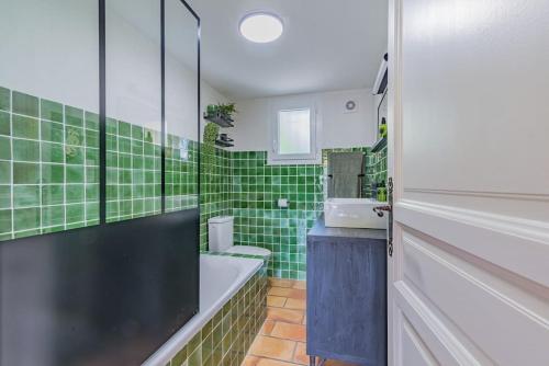baño de azulejos verdes con bañera y lavamanos en Mazet Magnan, Rustic Luxury in Provence, en Piolenc