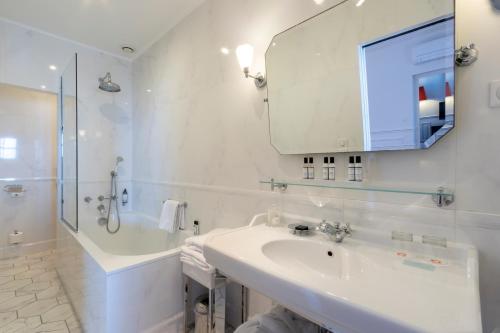 a white bathroom with a sink and a mirror at Hôtel Les Mouettes - Teritoria in Ajaccio