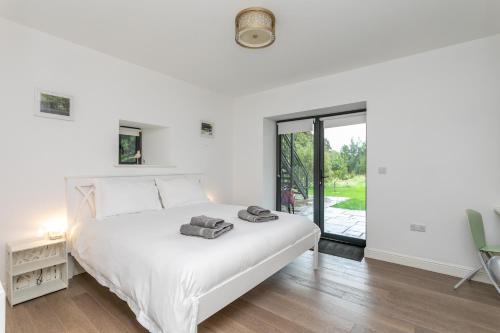 a white bedroom with a bed and a sliding glass door at Riverbank Cottage in Lancaster