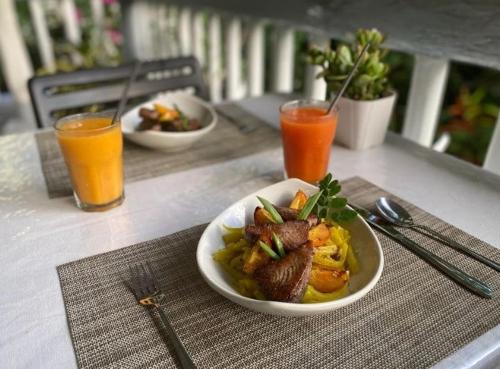a table with a plate of food and two glasses of orange juice at The Three P Beach Resort & Dive Center in Romblon