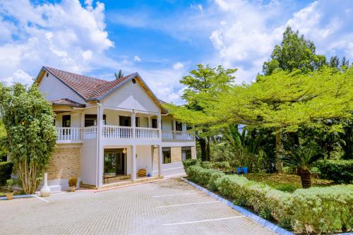 a white house with a driveway and trees at Nature Kigali in Kigali