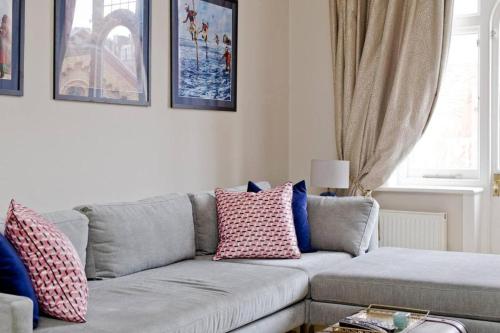 a living room with a gray couch with colorful pillows at Stylish London Getaway in the Heart of the City in London