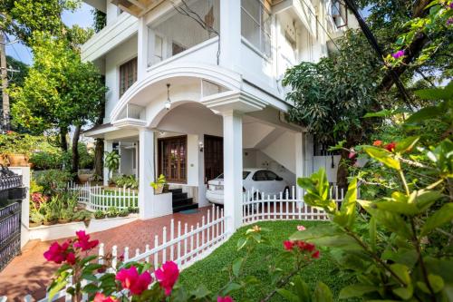 una casa bianca con una recinzione bianca e fiori rosa di Homested Homestay Fort Kochi a Cochin