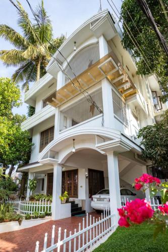 a white house with a white fence and pink flowers at Homested Homestay Fort Kochi in Cochin