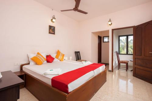 a bedroom with a large bed with red and yellow pillows at Homested Homestay Fort Kochi in Cochin