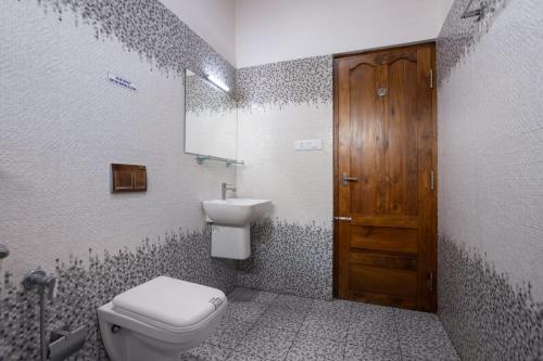 a bathroom with a toilet and a sink and a wooden door at Homested Homestay Fort Kochi in Cochin