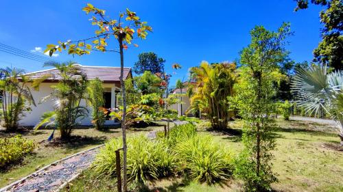 a garden with trees and a house at Isan Golf & Adventure Hotel in Udon Thani