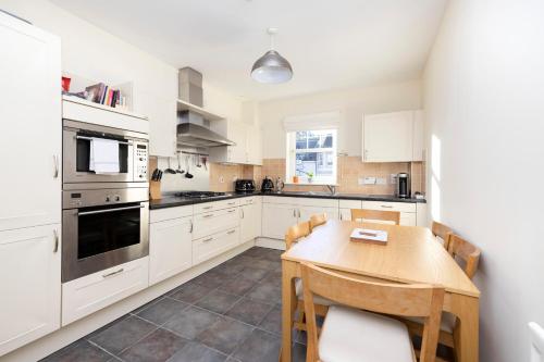 a kitchen with white cabinets and a wooden table at JOIVY Modern Flat with Free Parking in Edinburgh