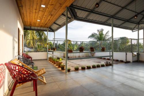 a screened porch with a red chair on a patio at Homested Homestay Fort Kochi in Cochin