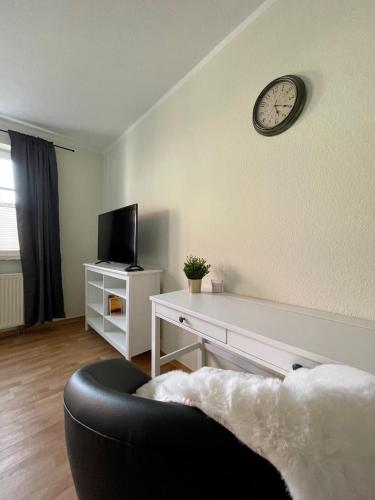 a living room with a couch and a clock on the wall at Ferienwohnungen Anne in Schönebeck