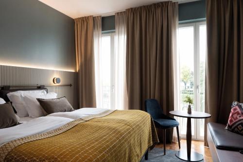 Elite Stadshotellet Karlstad, Hotel & Spa في كارلشتاد: غرفه فندقيه بسرير وكرسي ونافذه