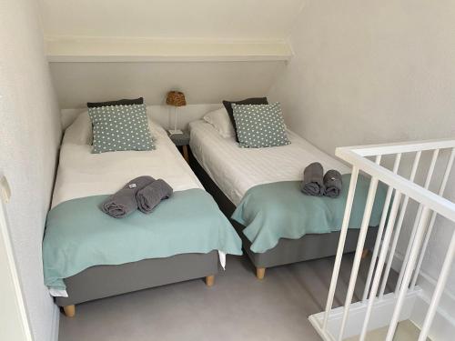 two twin beds in a room with a staircase at Zilt Noordwijk in Noordwijk aan Zee
