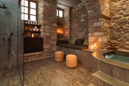 a bathroom with a tub in a stone wall at Castro Hotel Syros in Ermoupoli