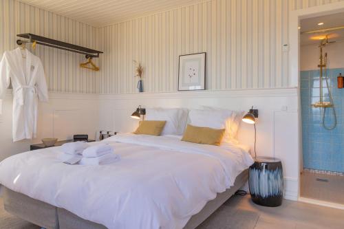 1 dormitorio con 1 cama blanca grande y toallas. en Allinge Badehotel, en Allinge