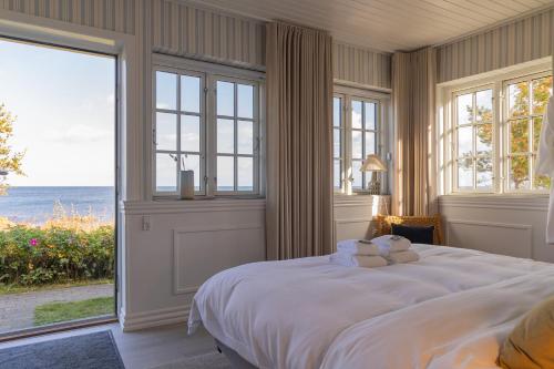 a bedroom with a large white bed with large windows at Allinge Badehotel in Allinge