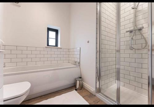 y baño con bañera, aseo y ducha. en The Dairy - Contemporary 1 bedroom cottage, 