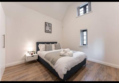 um quarto branco com uma cama com um urso de peluche em The Dairy - Contemporary 1 bedroom cottage 
