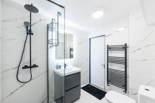 a white bathroom with a shower and a sink at Seafront apartment with balcony, parking and sea views in Aberystwyth