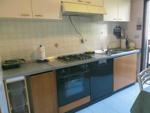 a kitchen with a stove and a sink at Mansarda tra le Dolomiti di Brenta in Bocenago