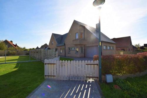 a house with a white fence in the yard at Chambre d'hôte Blankenberge in Blankenberge