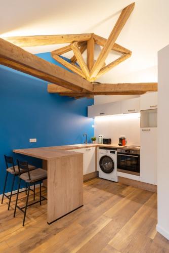 une cuisine avec une table en bois et un mur bleu dans l'établissement Le Favori de Montesquieu, à Nancy